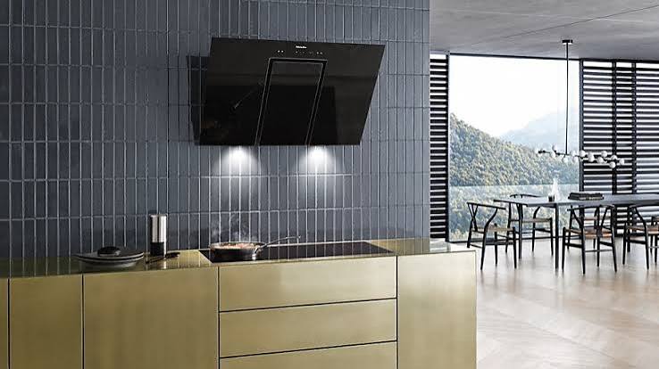 Miele zwarte schuine wandafzuigkap boven messing keuken